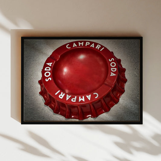 A framed image of a red cap with the words "SODA" and "CAMPARI" printed on it.