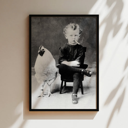 a black and white photo of a boy sitting in a chair next to a chicken