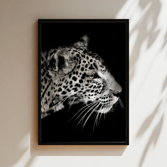 A close-up black and white photograph of a leopard's face, with its distinctive spotted pattern and intense gaze.