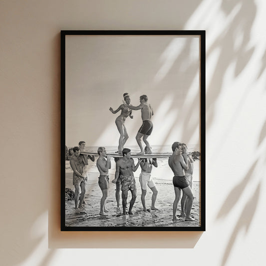 a black and white photo of a group of people on a surfboard