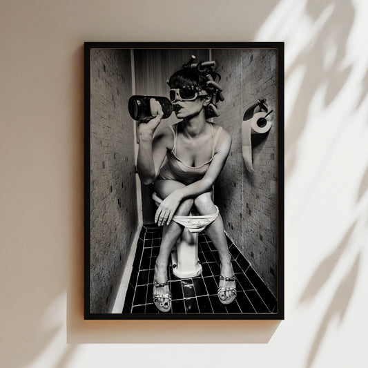 A black and white image of a woman sitting on a toilet in a bathroom, wearing sunglasses and holding a bottle.