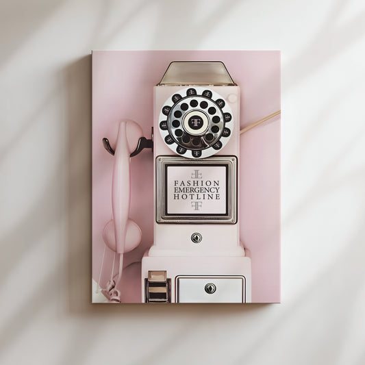 A vintage pink rotary phone with a sign that reads "FASHION EMERGENCY HOTLINE" is displayed against a pink background.