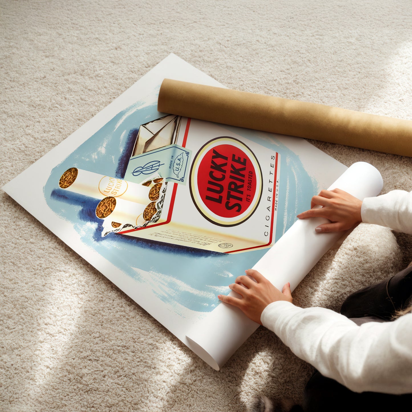 A person is holding a roll of paper and placing it on top of a poster featuring an illustration of Lucky Strike cigarettes.