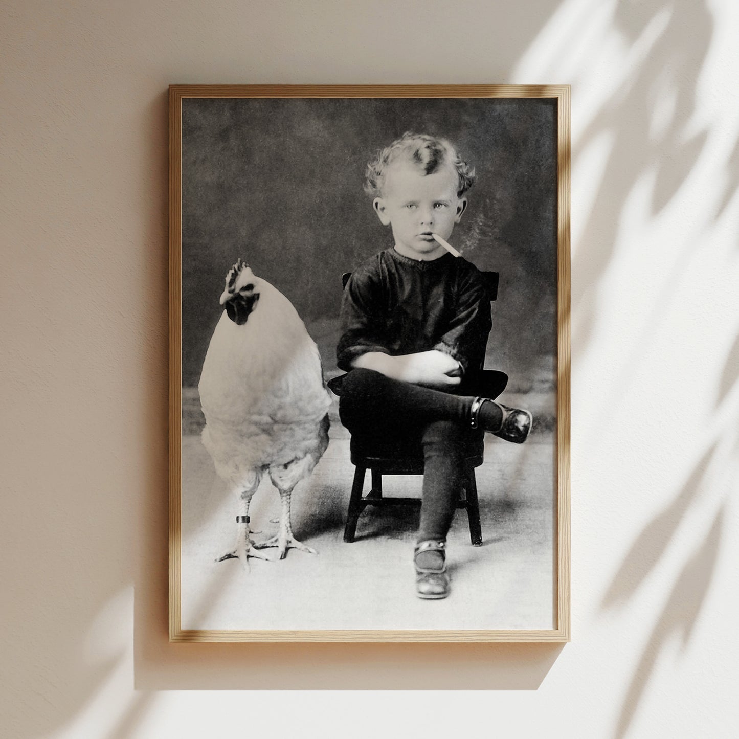 a black and white photo of a boy sitting in a chair next to a chicken