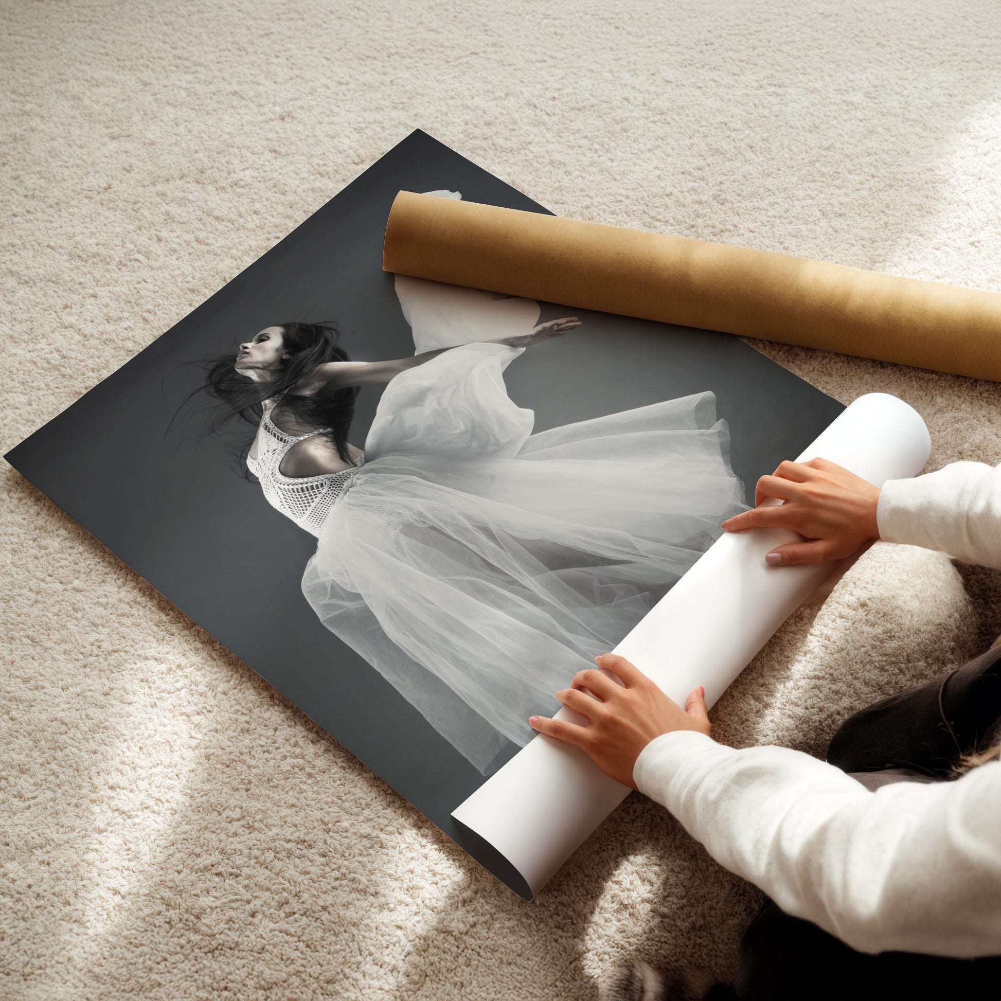 A person is carefully handling a large roll of paper, which appears to be a poster or canvas, as they lay it out on the floor.