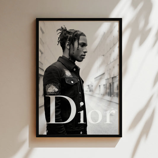 A black and white portrait of a young man with dreadlocks wearing a denim jacket, standing in an urban setting.