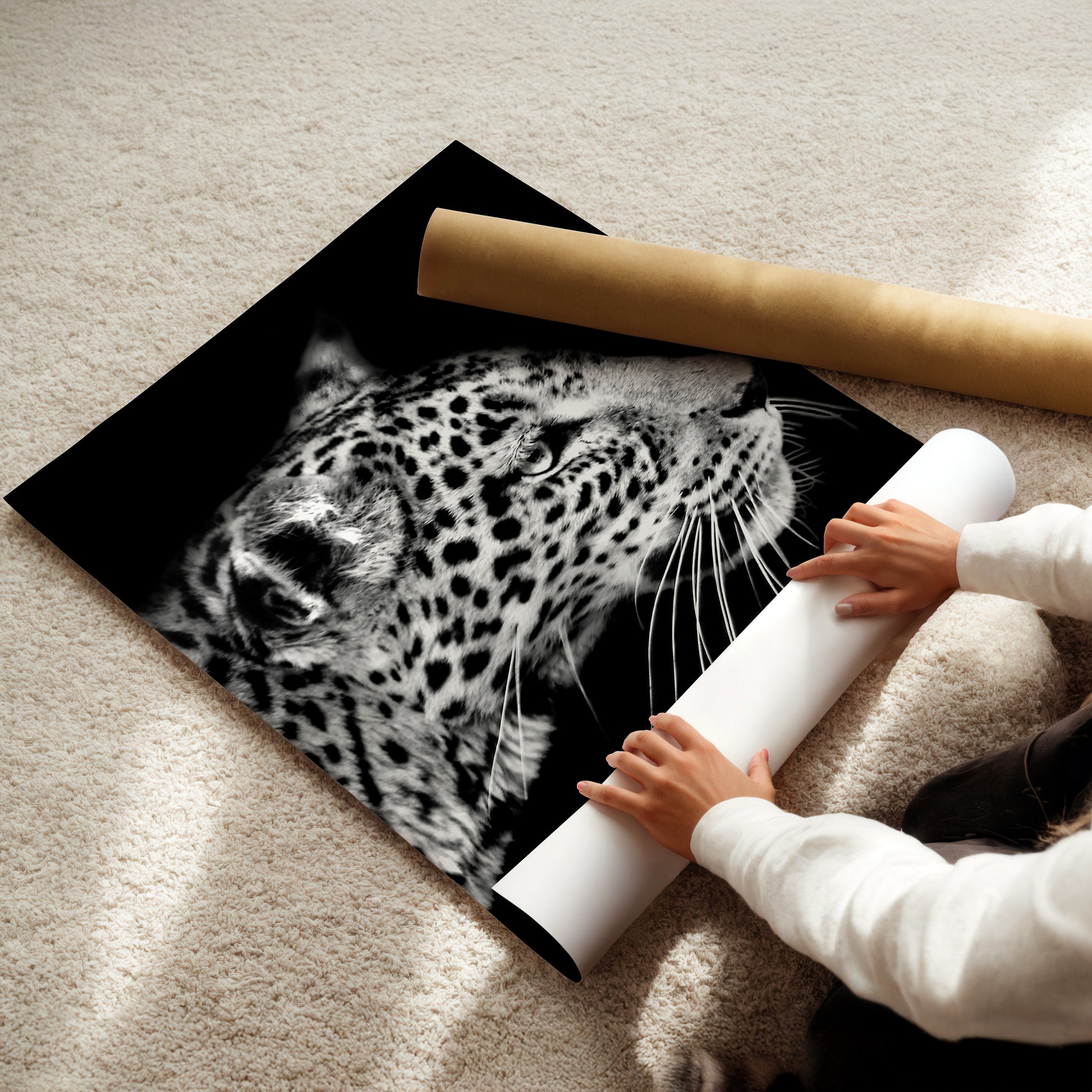 A person is holding a roll of paper and placing it under a large black and white photograph of a leopard's face.