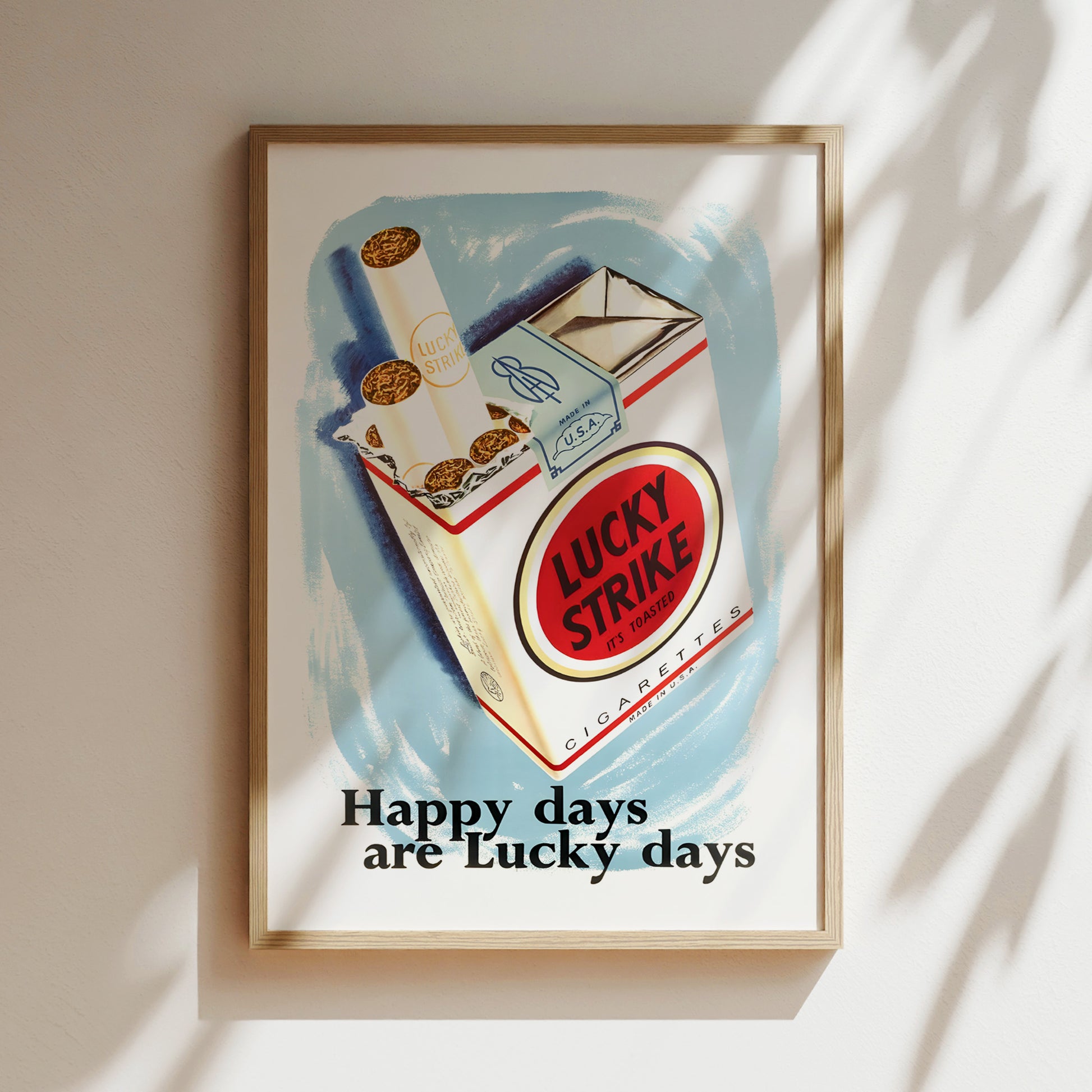 The image is a framed poster with an illustration of Lucky Strike cigarettes, accompanied by the text "Happy days are Lucky days".