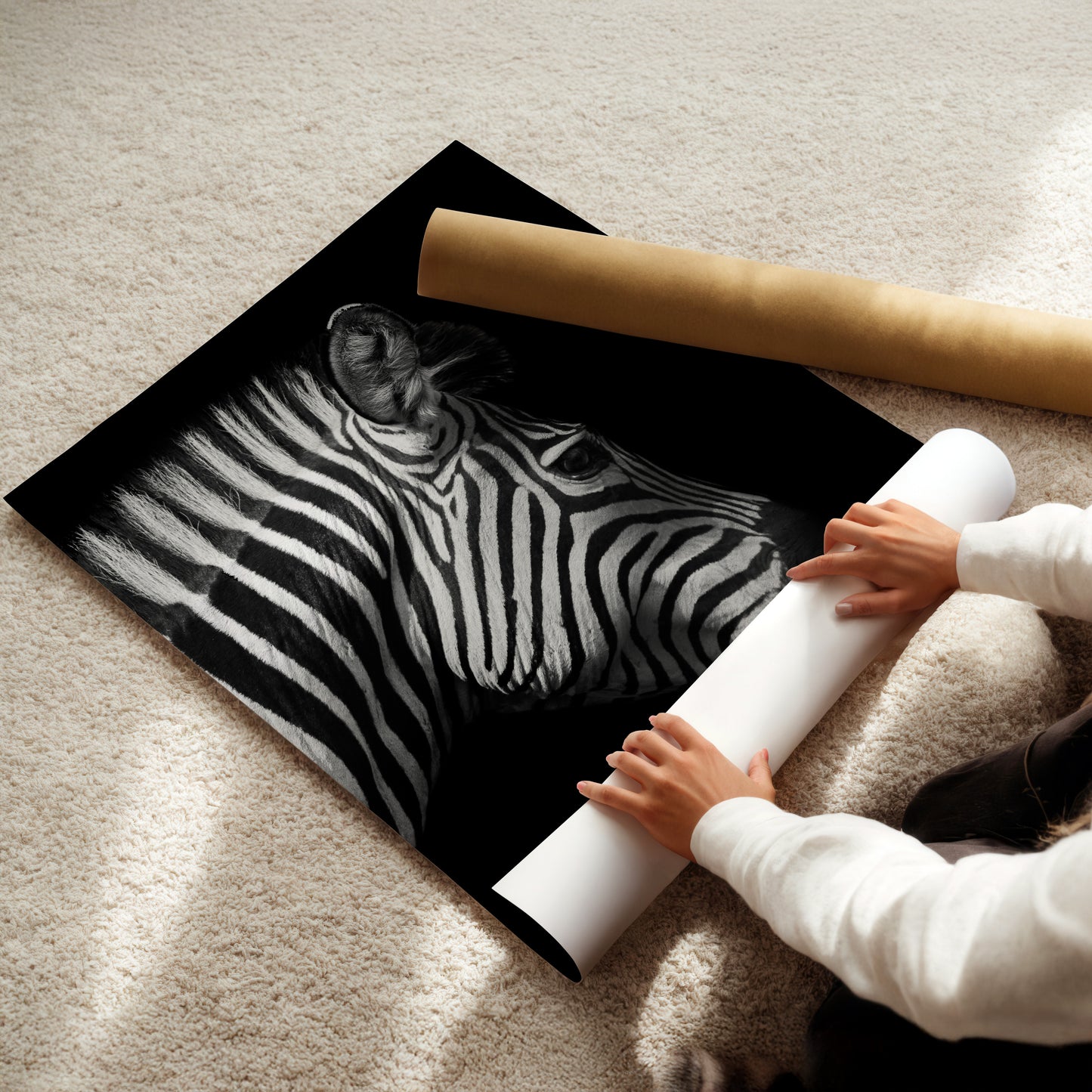 A person is holding a roll of paper and placing it under a large black and white photograph of a zebra's head.