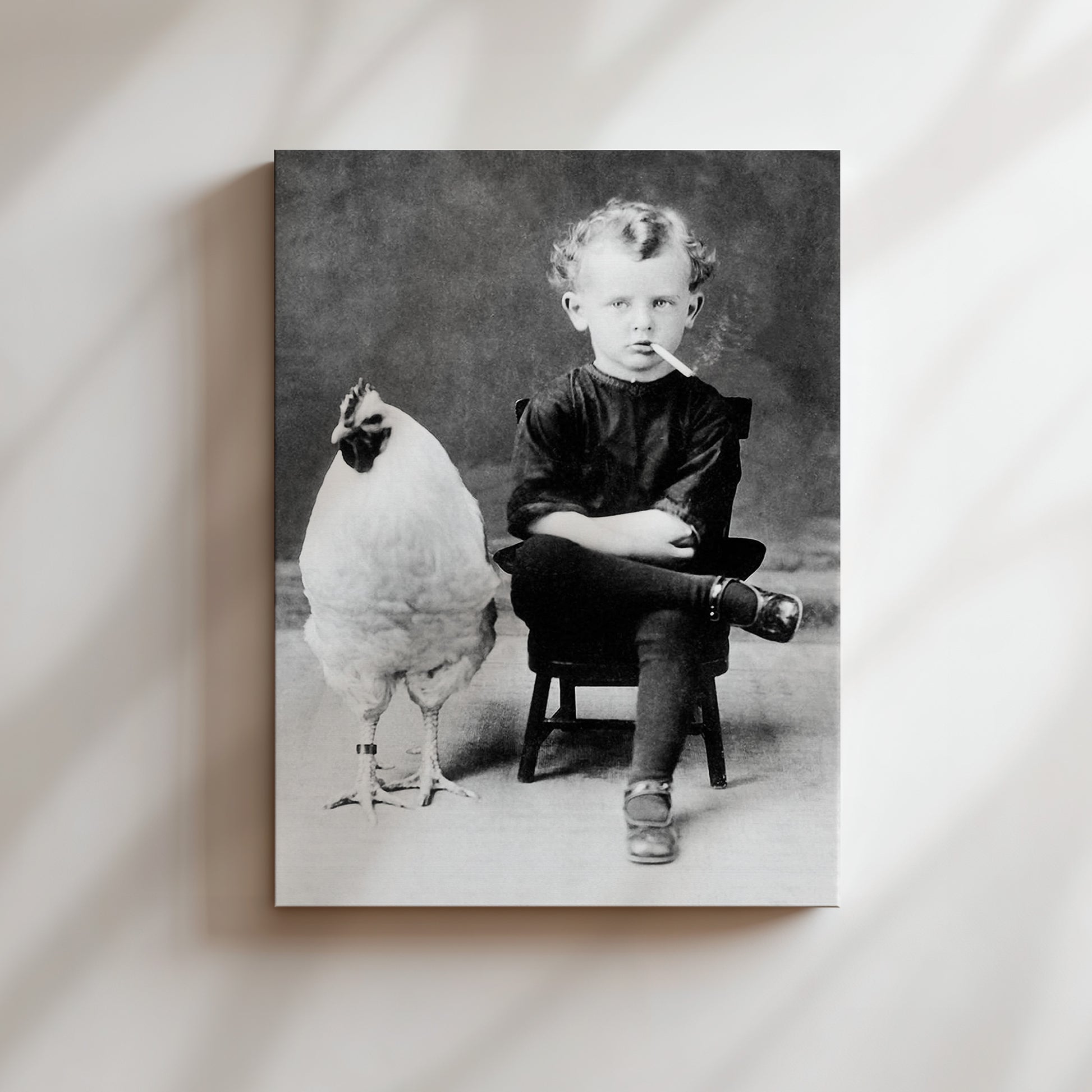 a black and white photo of a little boy sitting in a chair with a chicken