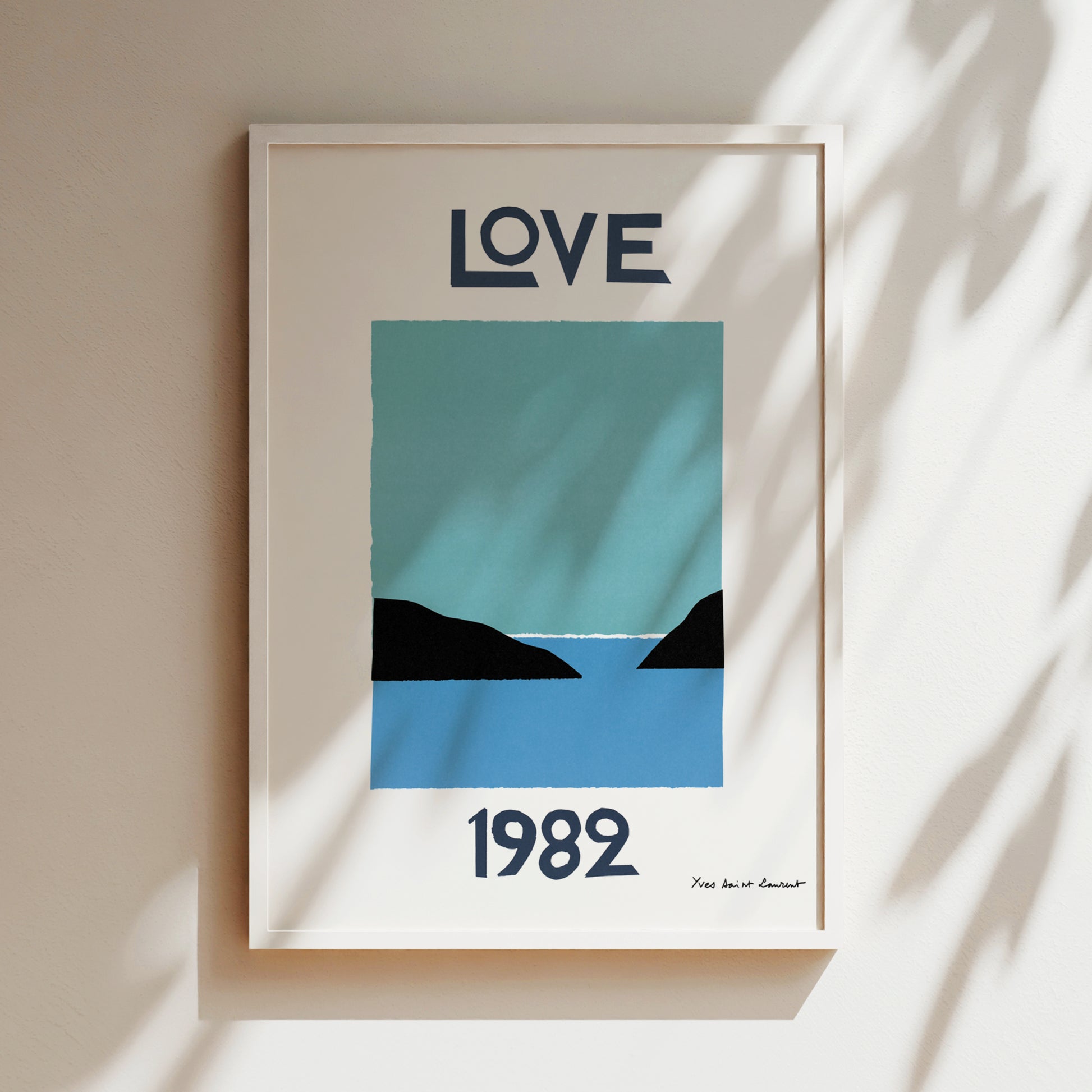 A framed poster with the word "LOVE" in large letters at the top and the year "1982" at the bottom. The poster also features a simple illustration of a blue sky and a black silhouette of a mountain.