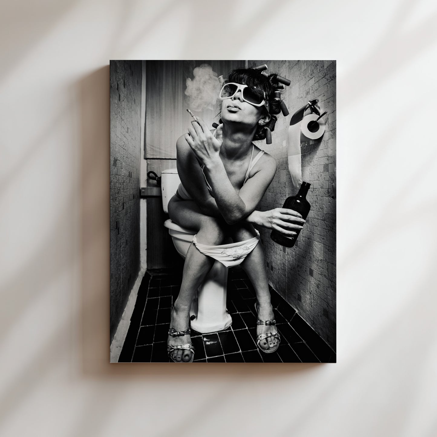 A black and white image of a woman sitting on a toilet in a bathroom, smoking a cigarette and holding a bottle of alcohol.