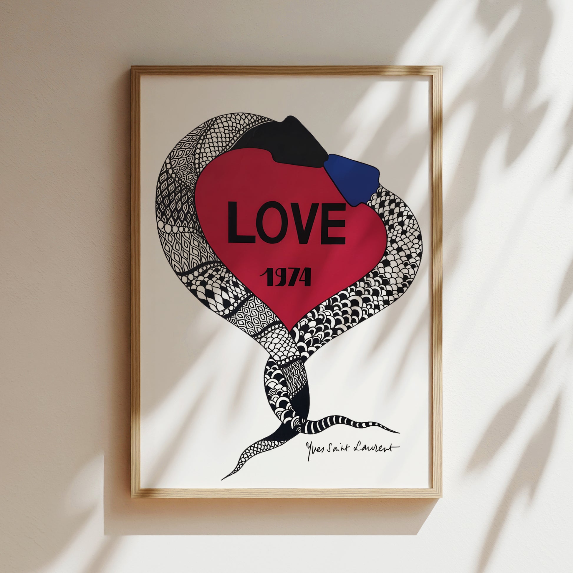 a framed artwork with a red heart-shaped design and a snake-like pattern. The word "LOVE" is prominently displayed in the center of the heart.