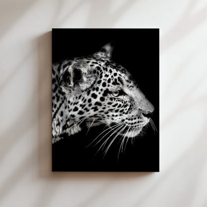 A close-up black and white portrait of a leopard's face, with its distinctive spotted fur and intense gaze.