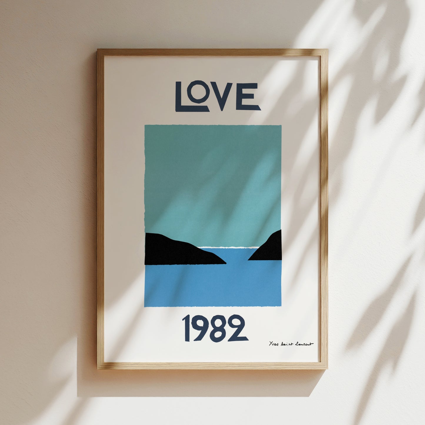 The image is a framed poster with a blue and black design depicting a serene landscape with mountains and a body of water. The text "LOVE" is prominently displayed at the top of the poster, and the year "1982" is shown at the bottom.