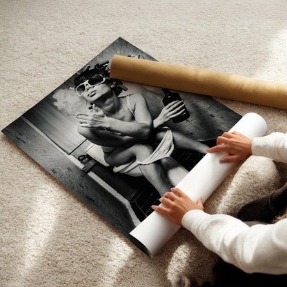 A person is holding a roll of paper and placing it under a large black and white photograph of a woman sitting on a toilet.