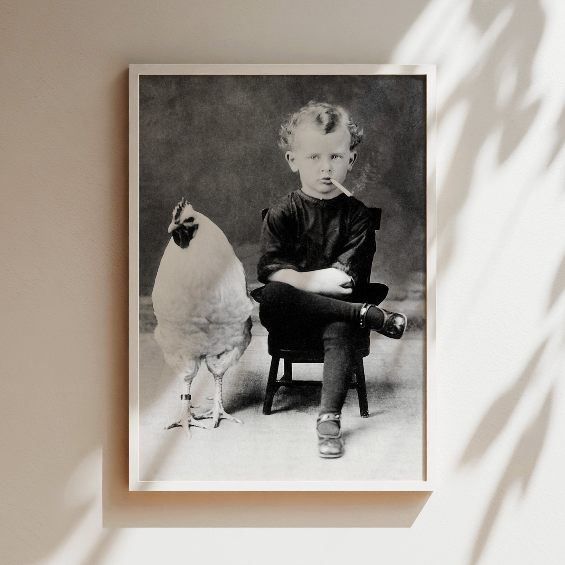 a black and white photo of a boy sitting in a chair next to a chicken