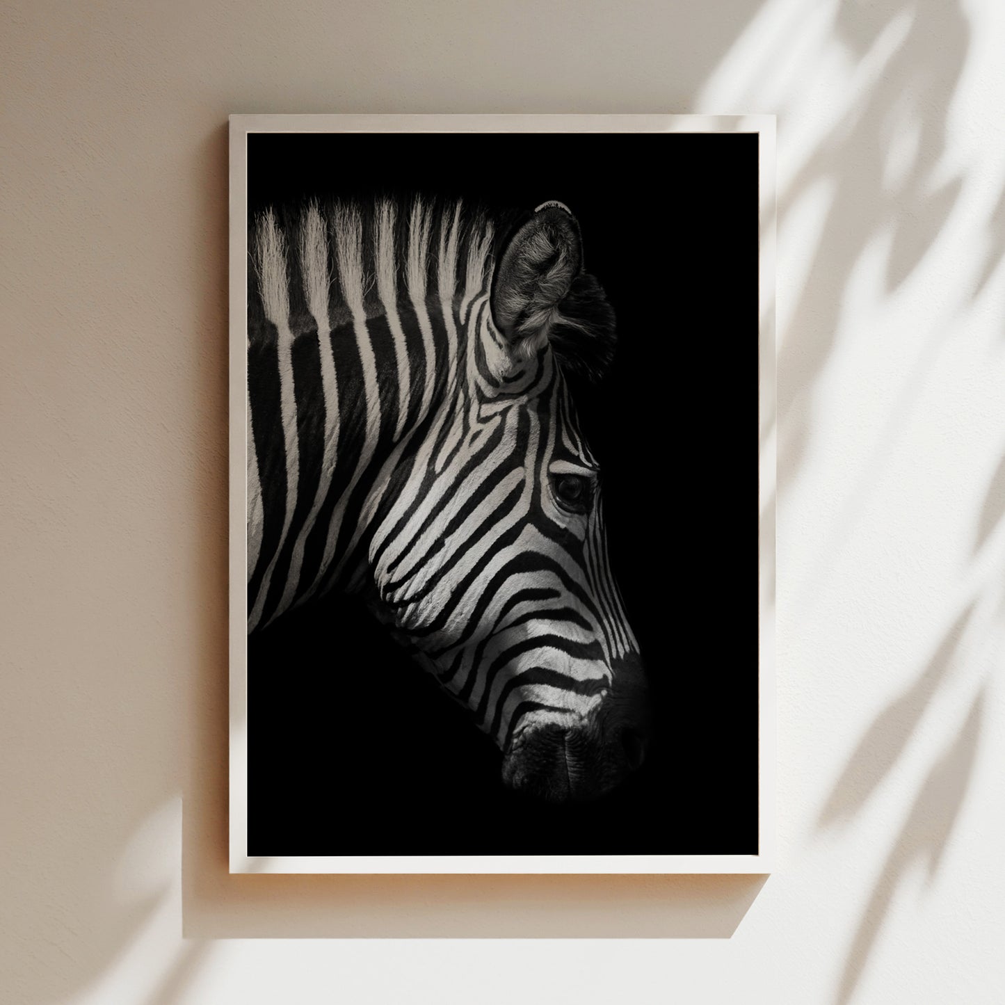 A black and white photograph of a zebra's head, with its distinctive striped pattern prominently featured against a dark background.