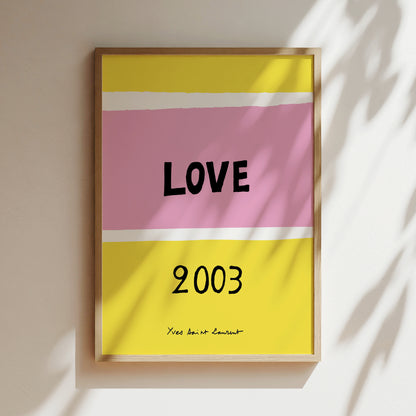 The image is a framed poster with a pink and yellow background, displaying the word "LOVE" in bold black letters. Below the word, the year "2003" is written in black.