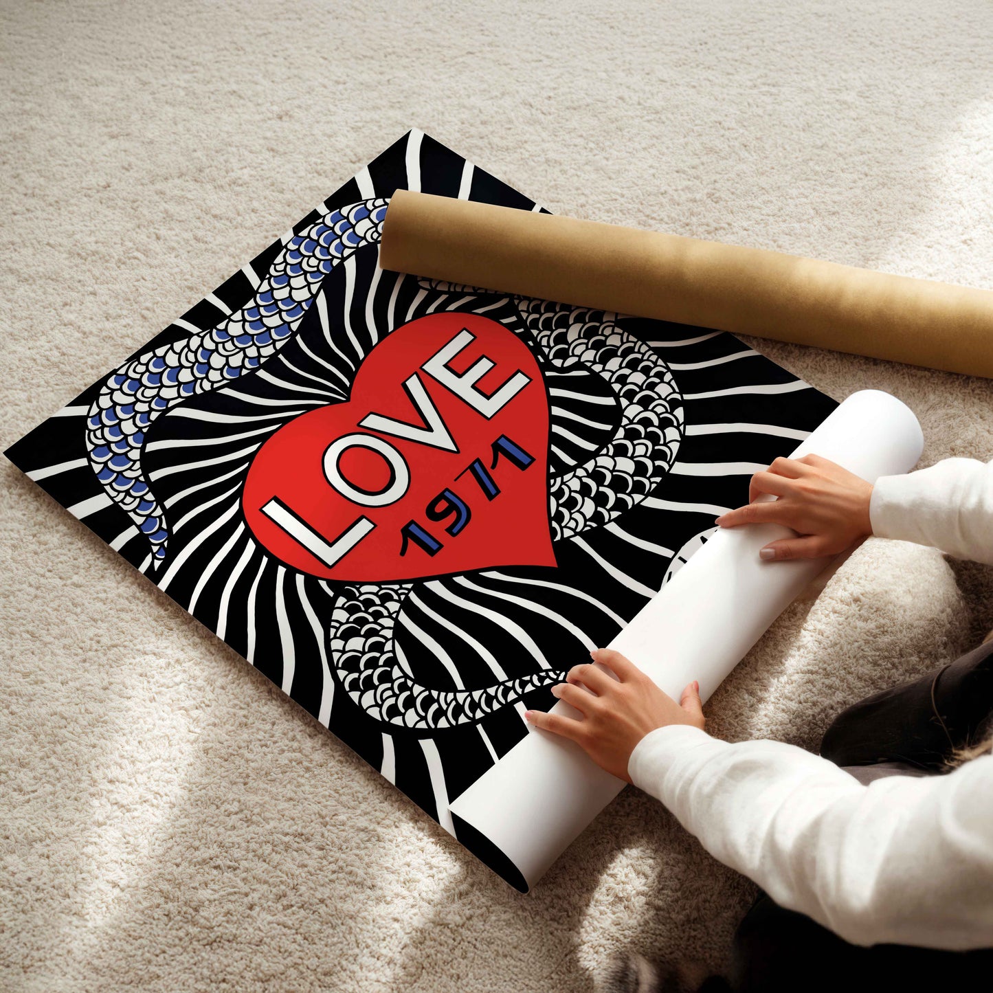 A person is rolling up a poster with a heart and snake design on it.