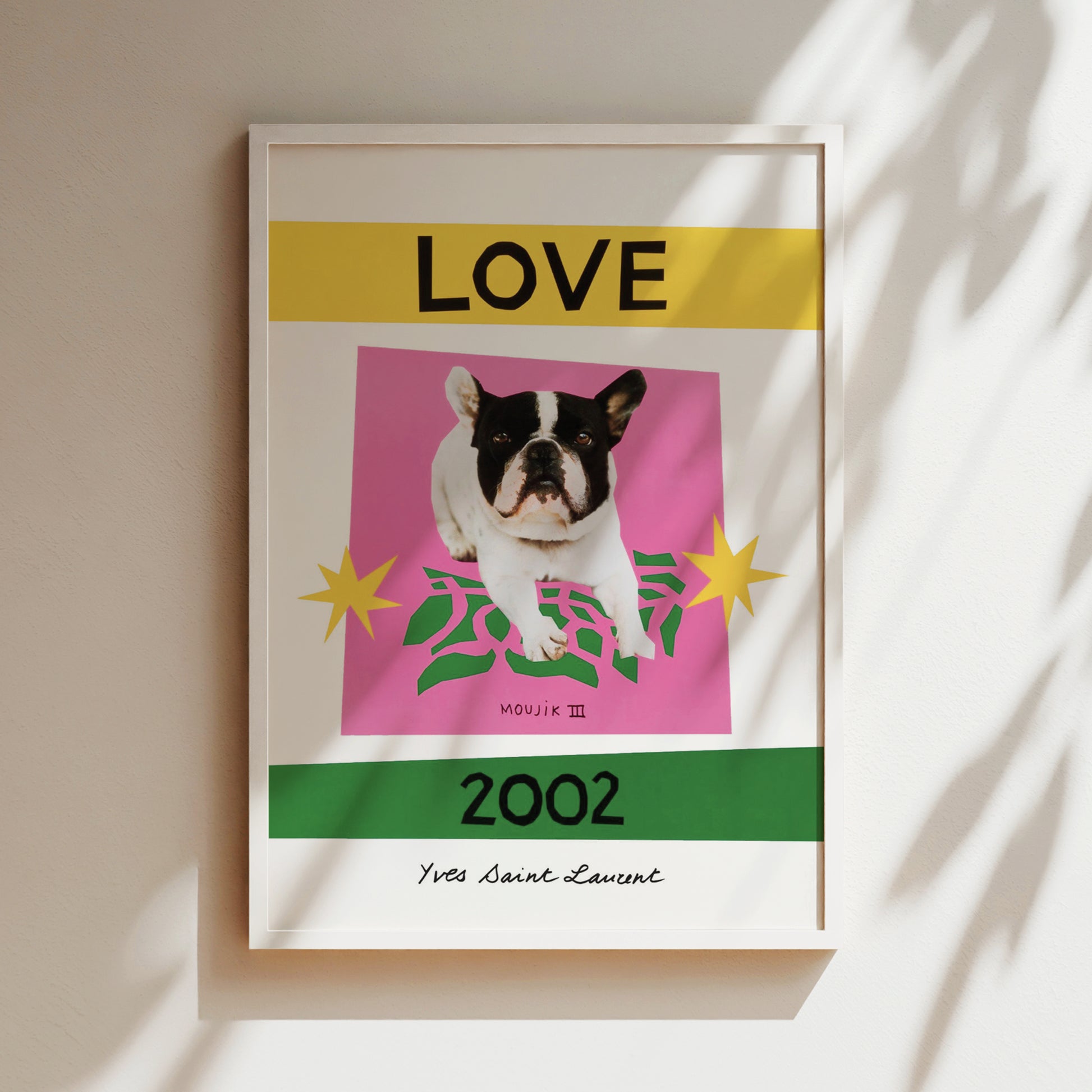 The image is a framed poster featuring a black and white dog on a pink background, with yellow and green accents. The text "LOVE" is prominently displayed above the dog, and "2002" is written below it. The poster also includes the text "MOUJK III" and "Yes Saint-Laurant" at the bottom.