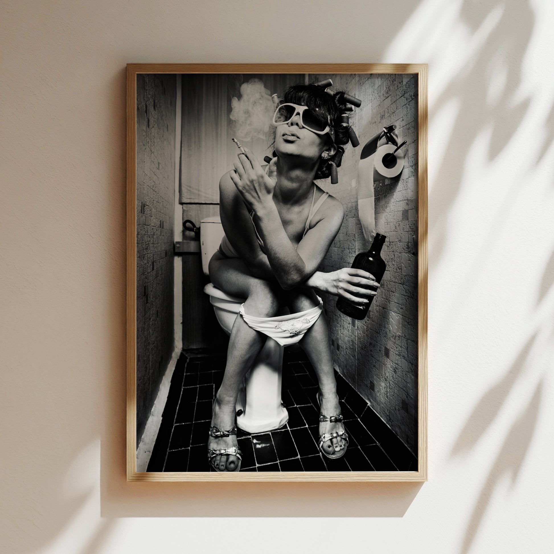 A black and white photograph of a woman sitting on a toilet in a bathroom, smoking a cigarette and holding a bottle.