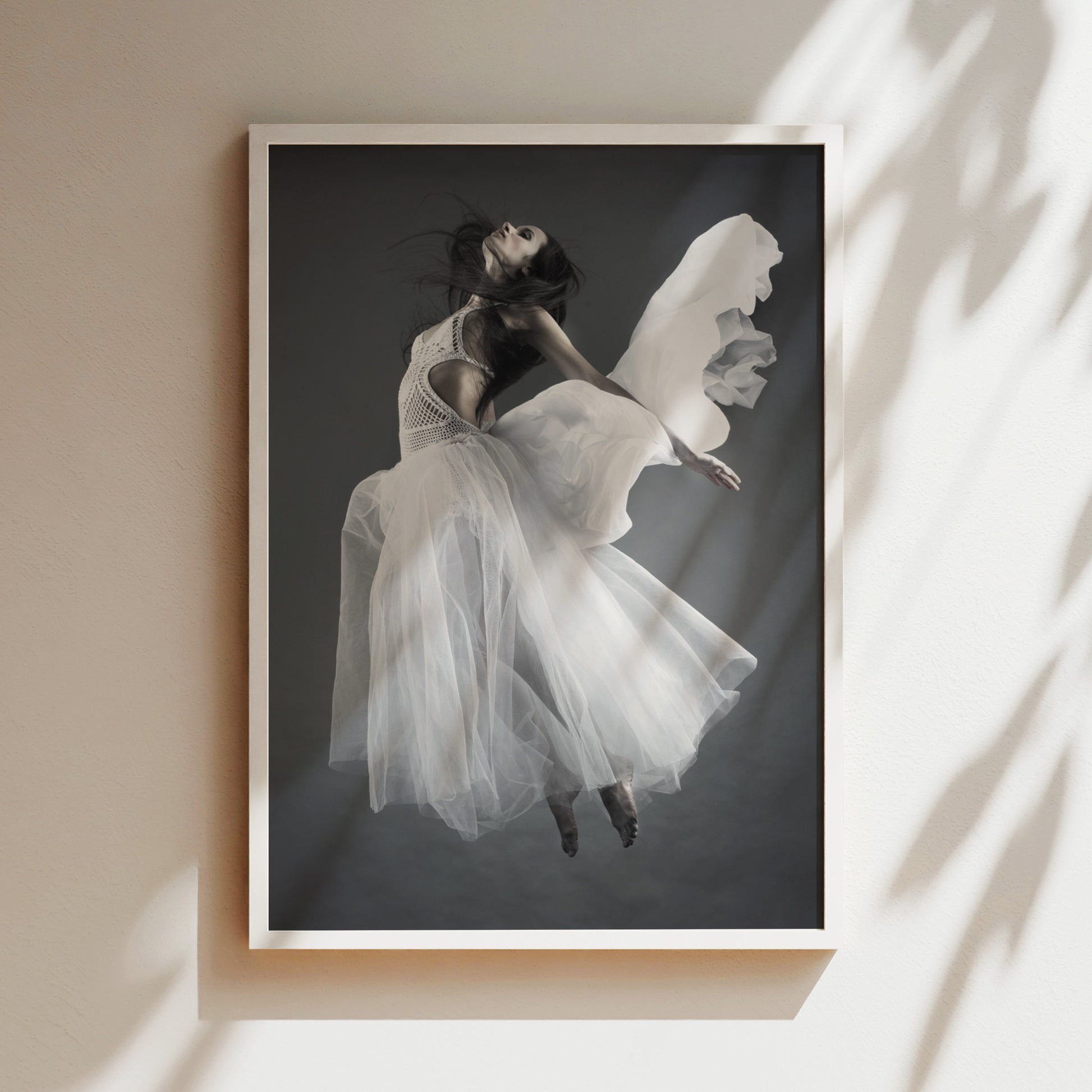 A woman in a flowing white dress is captured in mid-air, her hair blowing in the wind, creating a dynamic and elegant scene.