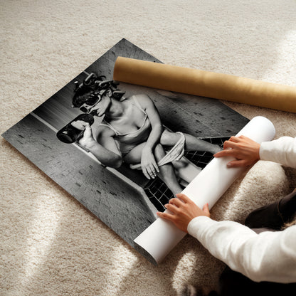 A person is holding a roll of paper and placing it under a black and white photograph of a woman sitting on a bench.
