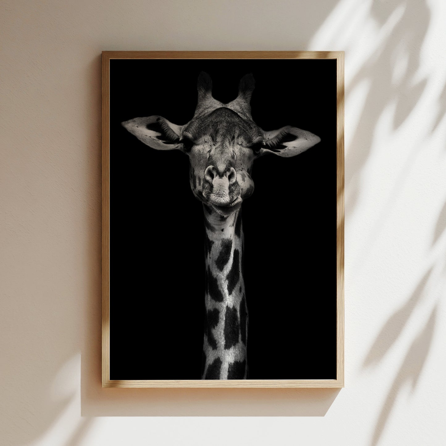 A framed black and white photograph of a giraffe's head, with its eyes closed and a serene expression, is displayed on a wall.