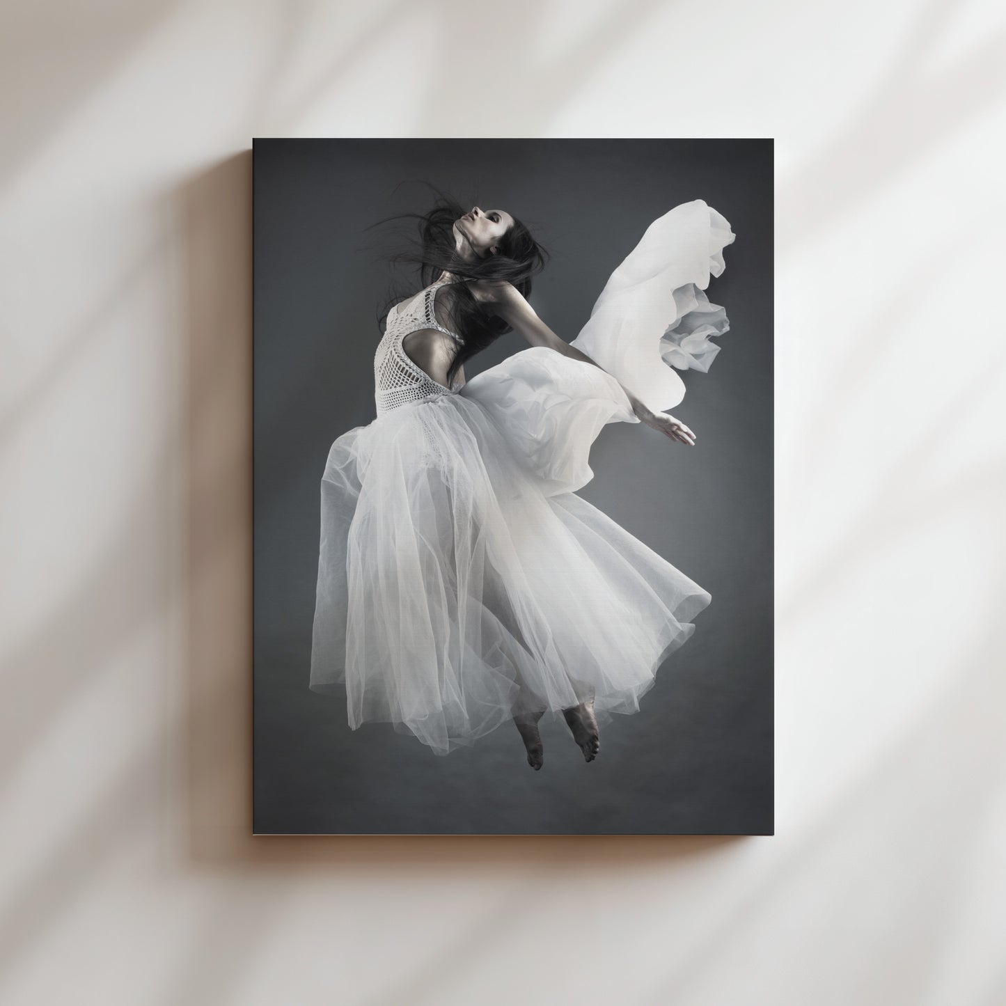 A woman in a flowing white dress is captured in mid-air, her arms outstretched, against a dark background.